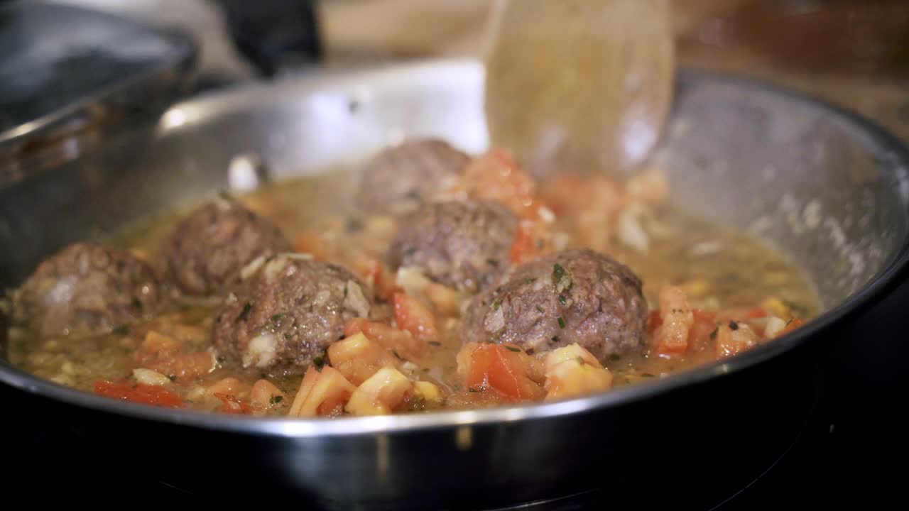 turning and cooking meatballs in a steel pan Preparing ingredients to make vegan beyond meatballs with spaghetti and meat sauce