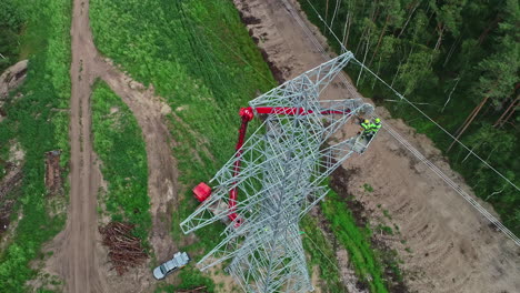 Toma-Superior-De-Los-Trabajadores-Que-Instalan-El-Pilón-De-La-Línea-Eléctrica-Con-La-Ayuda-De-Una-Grúa-Roja-Alta-Durante-El-Día