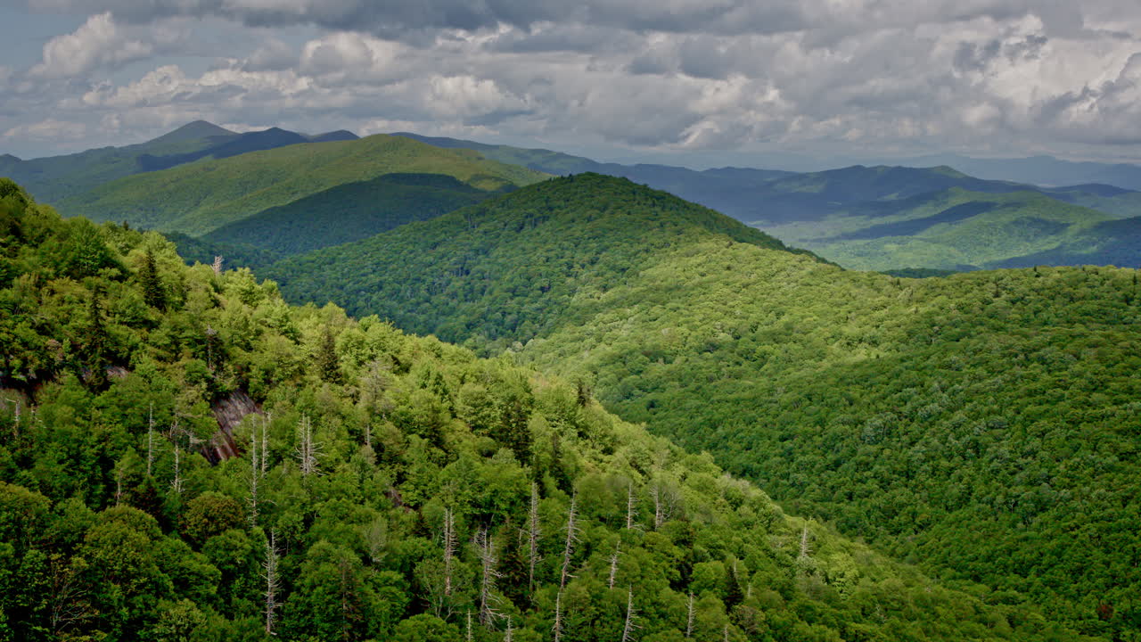 Dramatic aerial drone flight over the expansive Smoky Mountain wilderness, shrouded in fog, mist, and rain