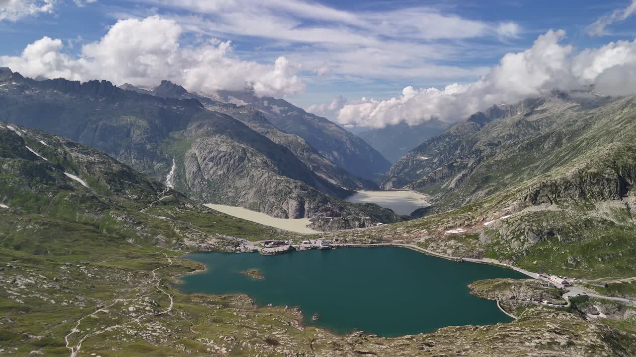 Aerial view of Lake Totensee, beautifully positioned within the mountain range in Obergoms, Switzerland, highlighting the striking contrast between the tranquil lake and the rugged alpine landscape.