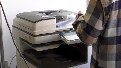 concepto de documentos comerciales: manos de un hombre de negocios trabajando en proceso de prensa de papel en una impresora láser en una oficina de escritorio ocupada