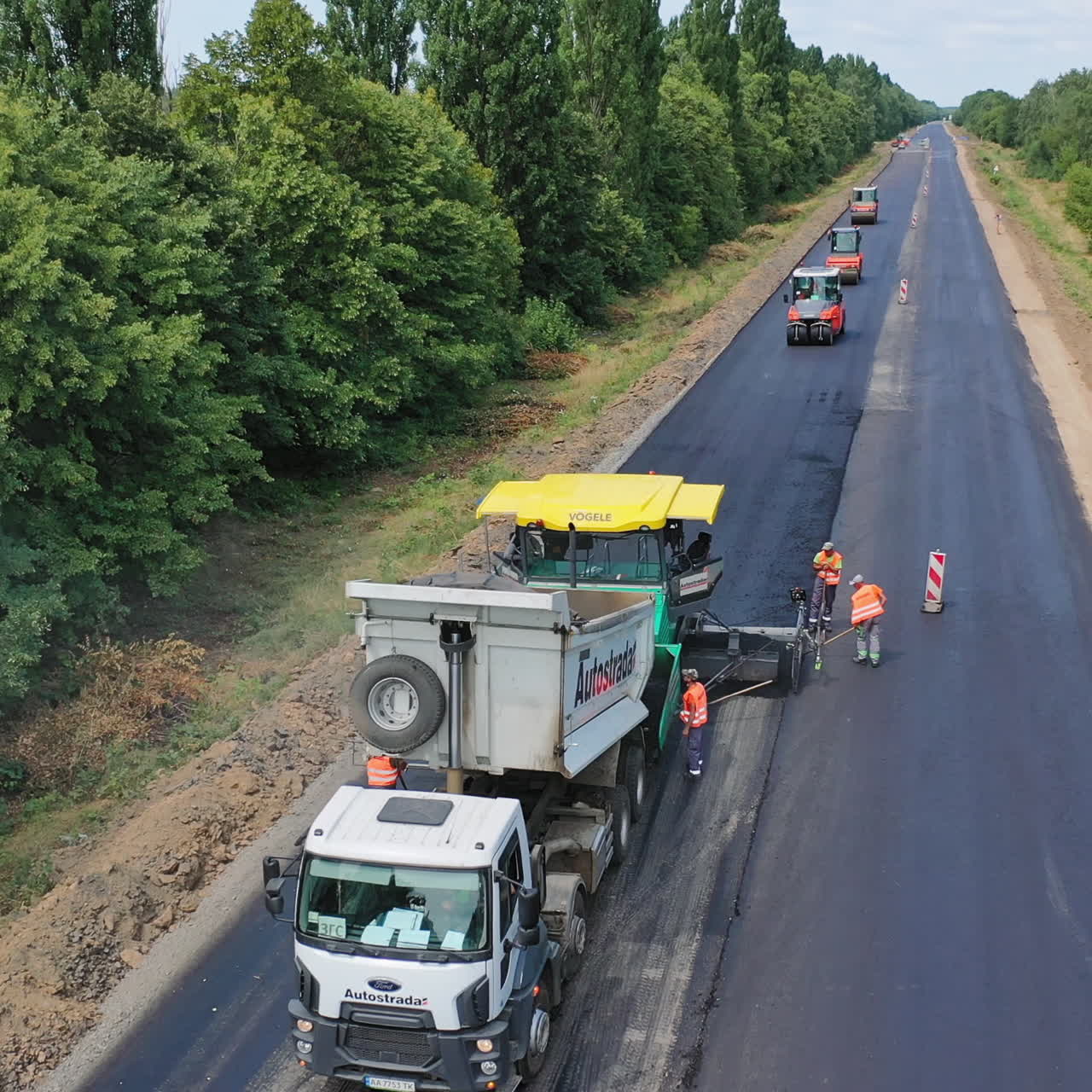 Aerial view of roadworks on the road. Heavy machinery laying new asphalt on the highway in a summertime. Asphalt road construction.