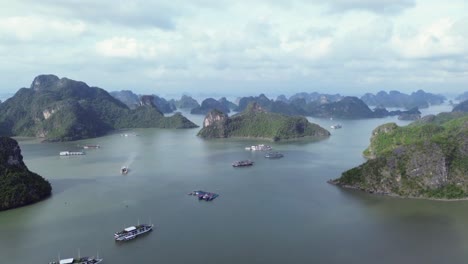 drone zoom in over cruise boats between karst limestone islands in the bay near cat ba island