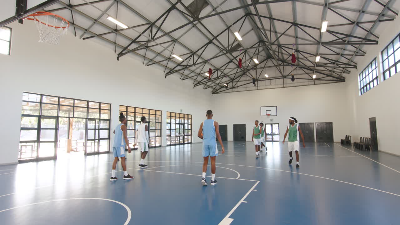 Multiracial male basketball players playing basketball, passing and throwing basketball in gym