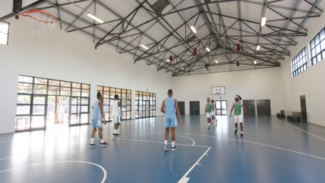 multiracial male basketball players playing basketball, passing and throwing basketball in gym