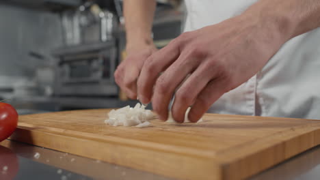 cook cutting onion on board