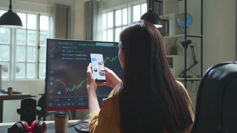 business woman trader investor analyst with financial stock market charts on desktop computer and shopping online on mobile at office