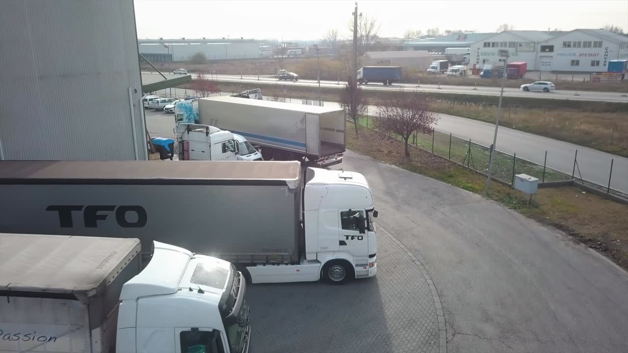 Aerial view of a cargo truck moving towards a road, next to industrial buildings