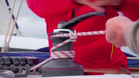 los marineros girando la manivela de un torno automático para ajustar la tensión de la cuerda - cerrar