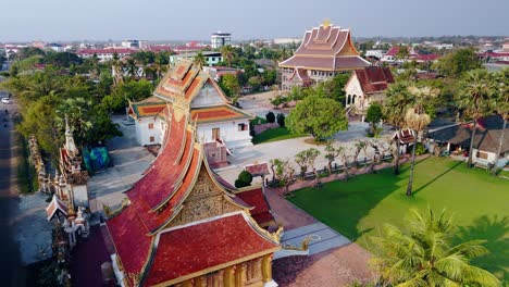 Traditional-arched-roof-pagoda-in-Laos-city-Savannakhet,-drone-aerial-fly-over-during-evening-sun-light