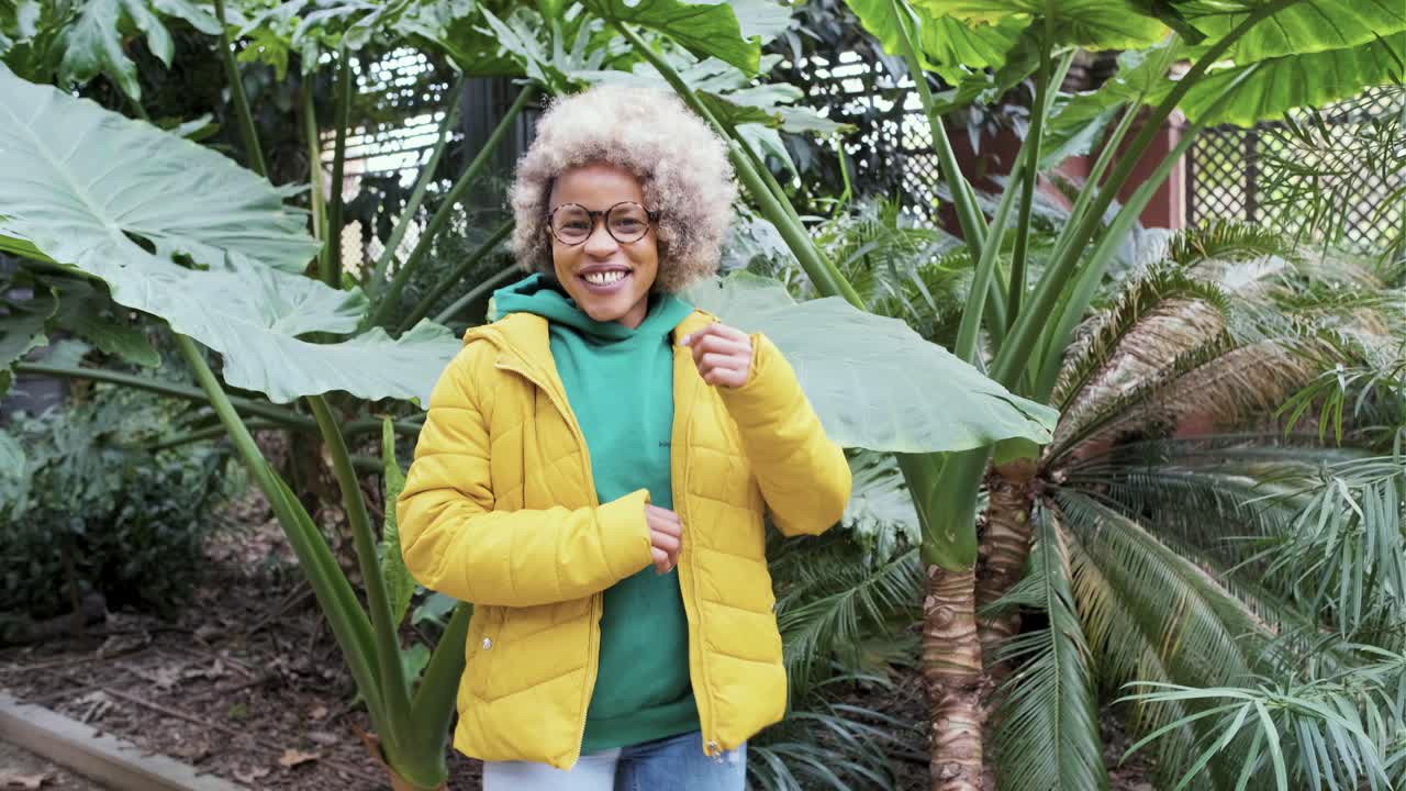 Woman in yellow jacket surrounded by tropical plants