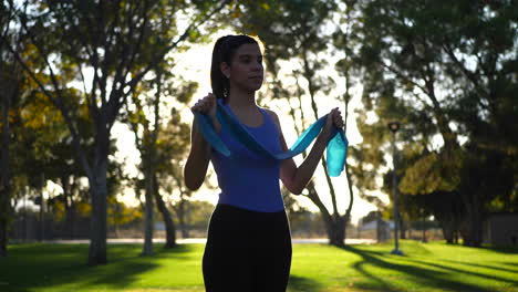 una hermosa joven que usa bandas de resistencia en su entrenamiento al aire libre y entrenamiento al atardecer en cámara lenta