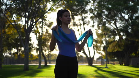 a beautiful young woman using resistance bands in her outdoor workout and exercise training at sunset slow motion