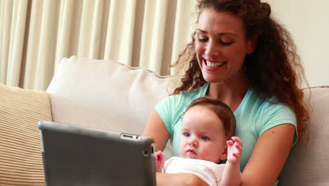 madre usando una tableta para conversar por video con su bebé en el regazo