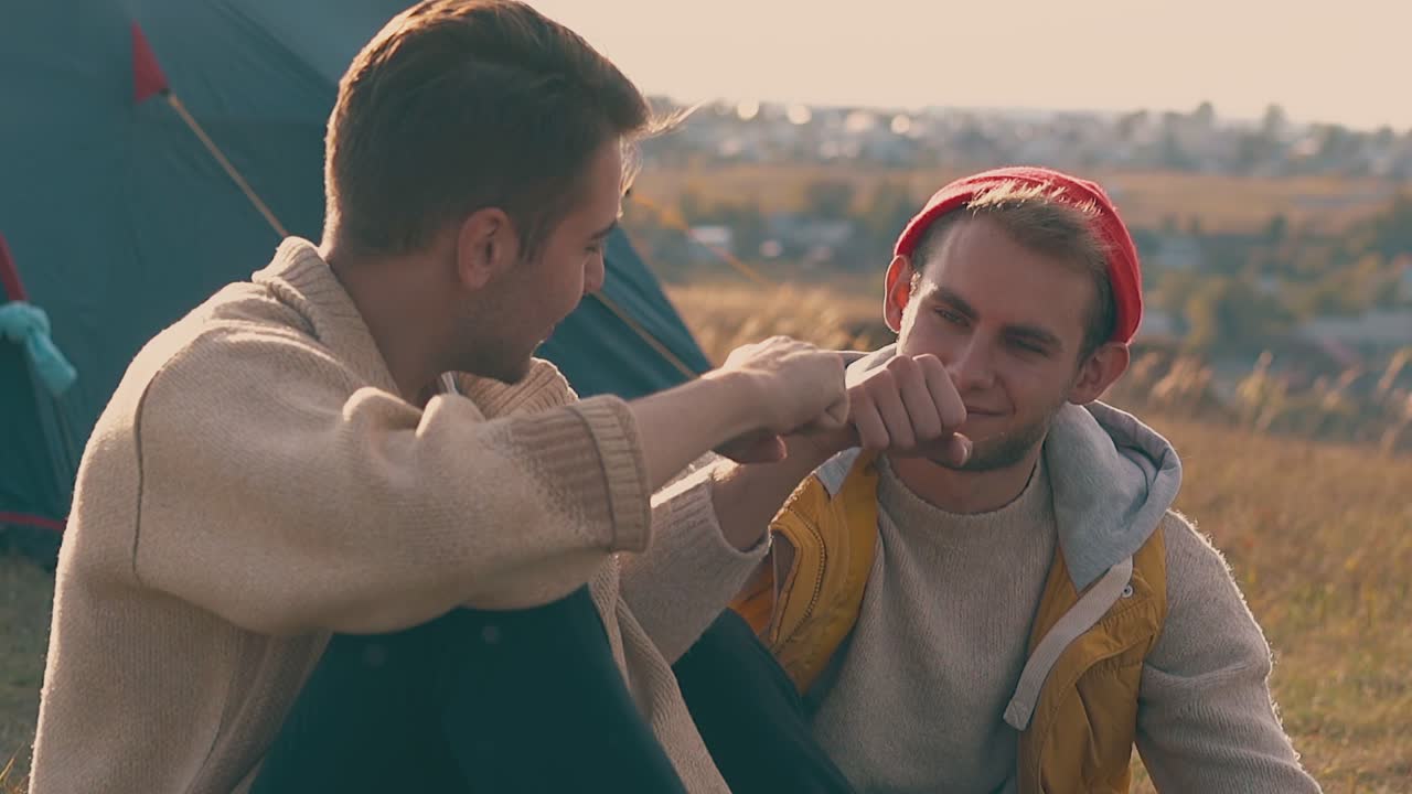 парень разговаривает с парнем и бьет кулаки дружно в голубой палатке