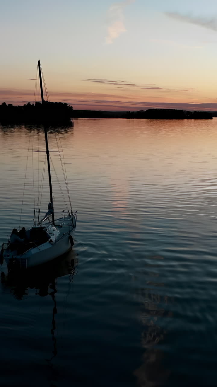 Barca a vela che galleggia su acque calme durante un tramonto serale splendido e colorato