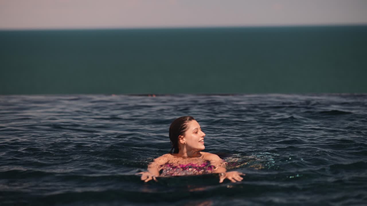 바다를 바라보는 수영장에서 수영하는 소녀