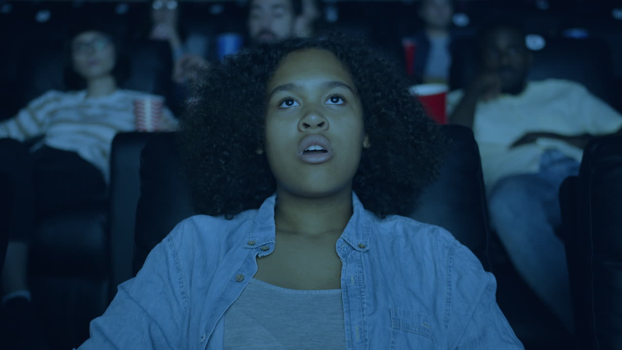 Teenager watching a movie in the theater, surprised