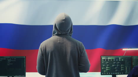 Ein-Russischer-Hacker,-Der-In-Einem-Staatlichen-Hacking-Raum-Mit-Der-Russischen-Flagge-Arbeitet