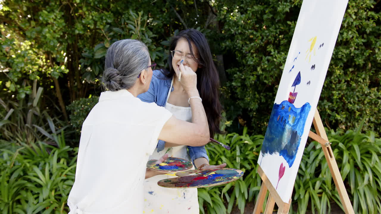 Painting on canvas, Asian grandmother and granddaughter enjoying outdoor art activity together