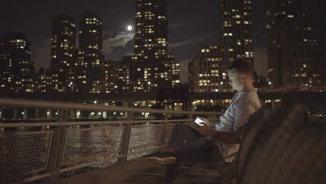 young caucasian businessman using tablet computer browsing the internet outdoors in the city. portrait shot of entrepreneur brainstorming ideas at night.