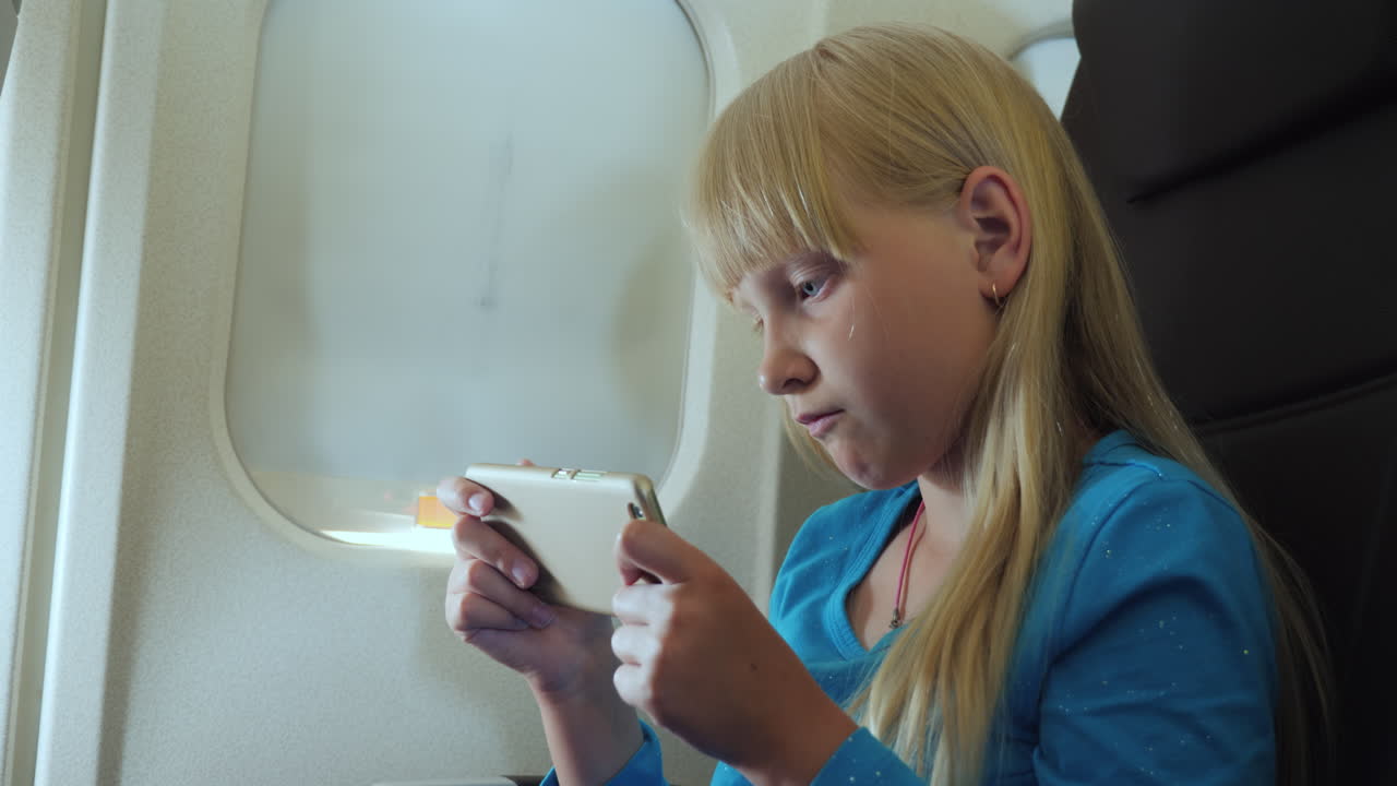 el niño juega en el teléfono inteligente en la cabina