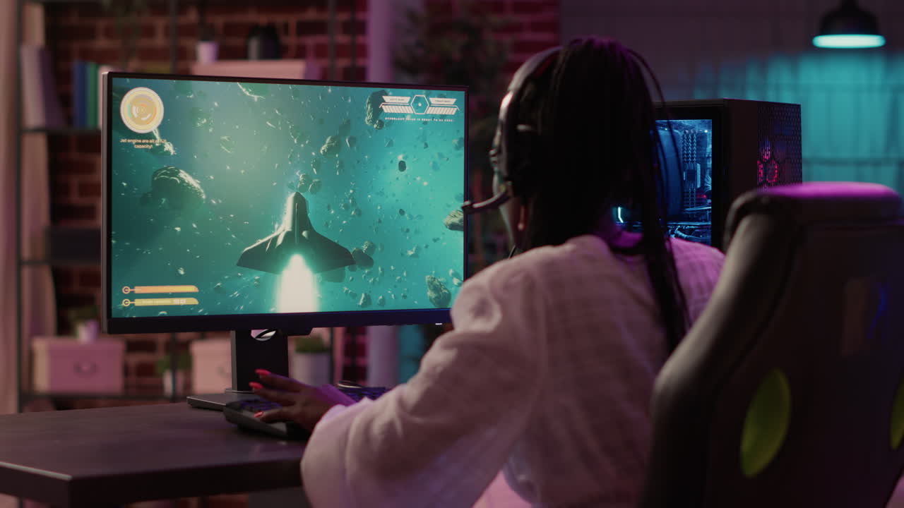 Over shoulder view of african american gamer girl playing space shooter simulation using pc gaming setup