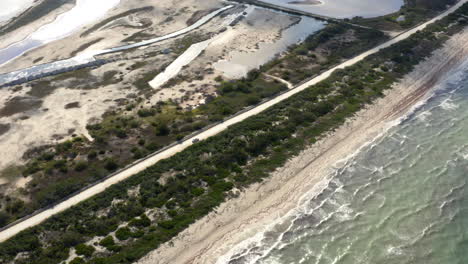 Car-driving-on-long-coastline-road-along-sand-beach-washed-by-waves