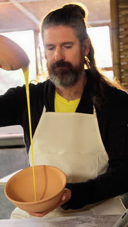 male potter pouring watercolor in bowl