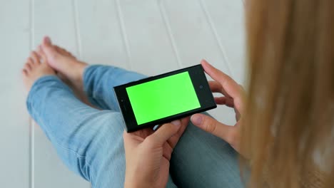 mujer usando un teléfono inteligente con pantalla verde