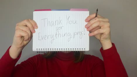 female young student holding up thank you sign during video lecture