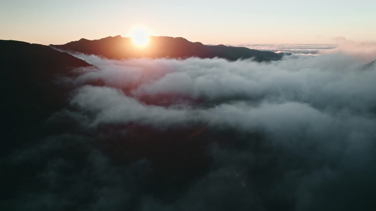 volando a nivel de las nubes en un valle, puesta de sol, sol brillando sobre el pico de la montaña, madeira