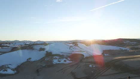 aerial view of riding motocross bike on sand dunes covered with snow, little sahara, utah