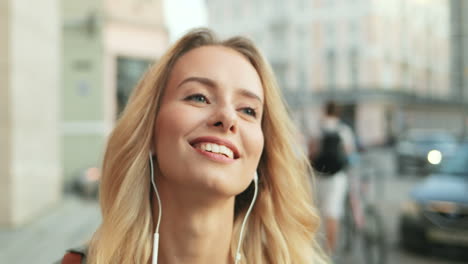 Vista-De-Cerca-De-Una-Mujer-Rubia-Caucásica-Caminando-Por-La-Calle-Y-Escuchando-Música-Con-Auriculares