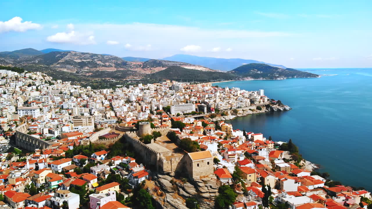 Aerial view of Kavala, a lot of buildings, Aegean sea coast, sea port, ancient fort, green hills in the distance, Greece
