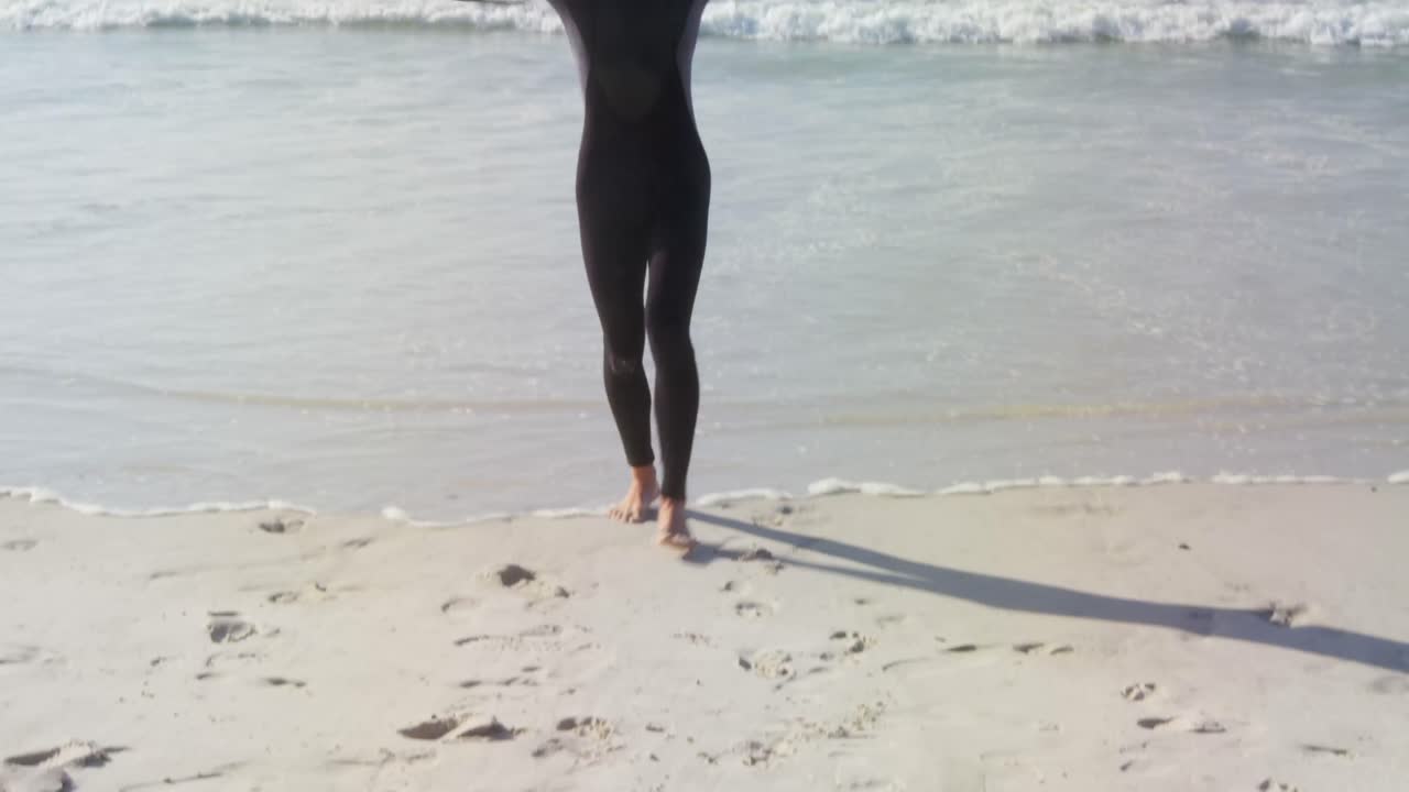 남자 서퍼 가 해변 4k 에서 머리 위 에 서프보드 를 들고 있다