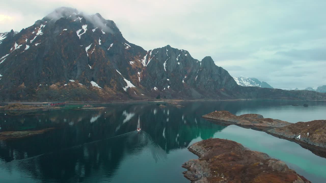 Aerial drone shot of a foggy ocean in Lofoten Norway. With rocks and mountains in the background.