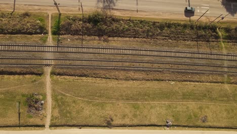 AERIAL---Railroad-tracks,-cars-on-a-street-in-Maschwitz,-Argentina,-top-down