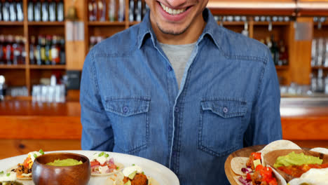 Waiter-holding-plate-of-mexican-food-in-bar-4k