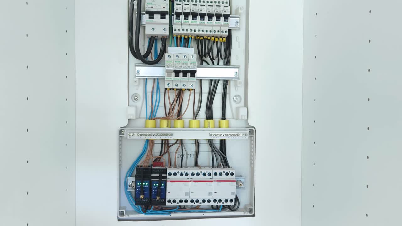 Close-up of an open electrical panel with various circuit breakers and intricate wiring