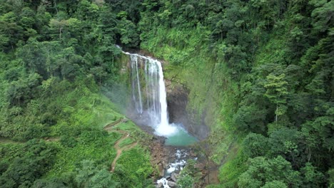 camión aéreo a la izquierda de la cascada eco chontales cayendo por una piscina natural rocosa rodeada de bosques verdes y densos, costa rica