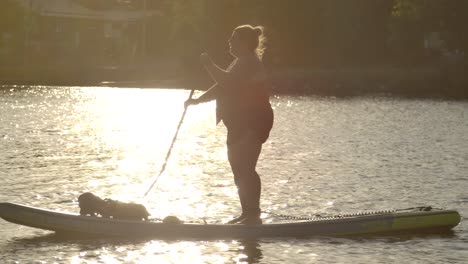 mujer paddle surf en el lago espumoso puesta de sol slomo