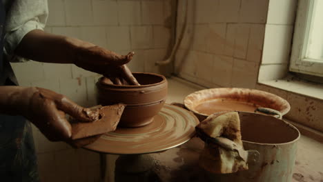 master working with wet clay pot in pottery. woman hands making line on product