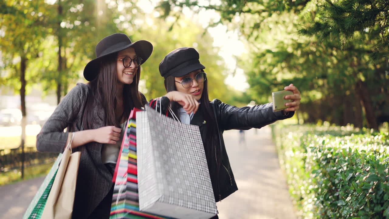 Two friends taking a selfie in a park after shopping