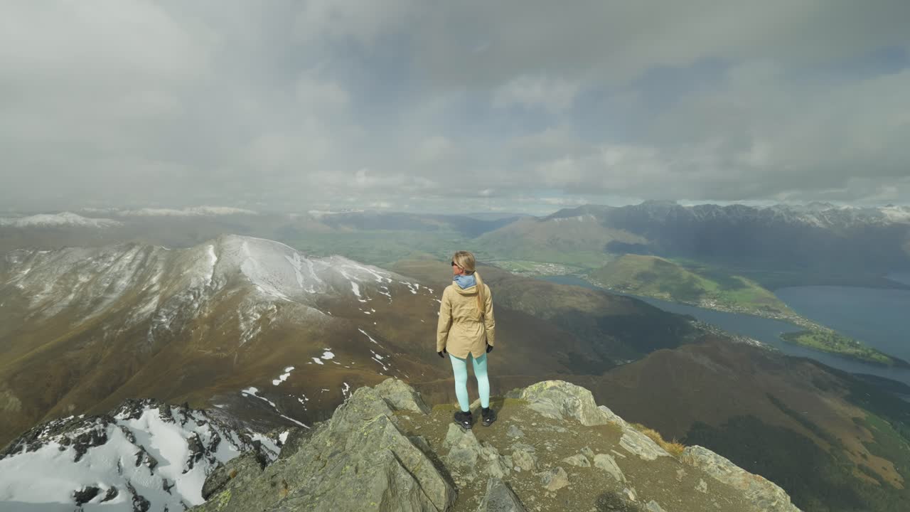 mujer de pie en la cima de la montaña disfrutando de una vista espectacular de los alpes del sur en nueva zelanda