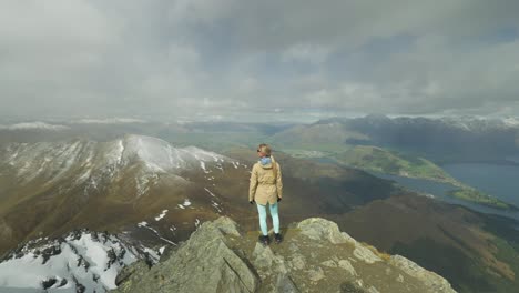 Woman-standing-on-mountain-peak-enjoying-spectacular-view-of-Southern-Alps-in-New-Zealand