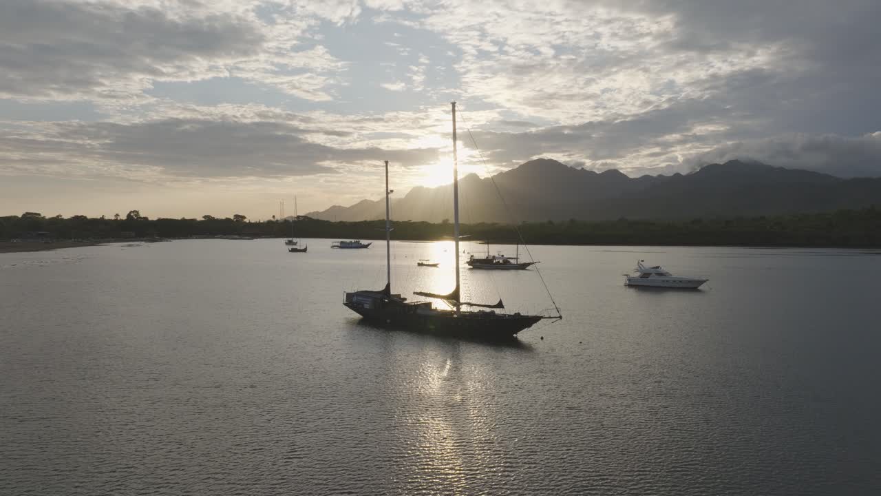 Vista con drone di barche in una baia tranquilla all'alba nel Parco Nazionale di Bali Occidentale, con montagne e costa tropicale riflesse nell'acqua, che cattura la natura serena, i viaggi e il paesaggio dell'isola.