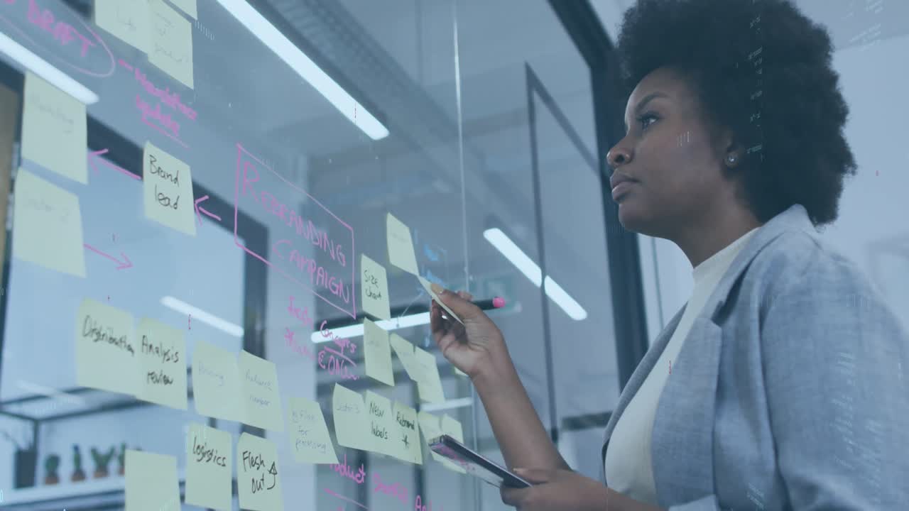 Animation of computer language, binary codes over african american woman sticking note on glass wall