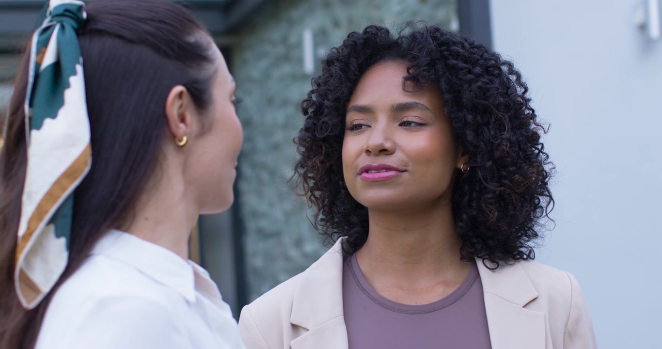 Diverse female team making eye contact by glass door, African American woman talking, saying hello