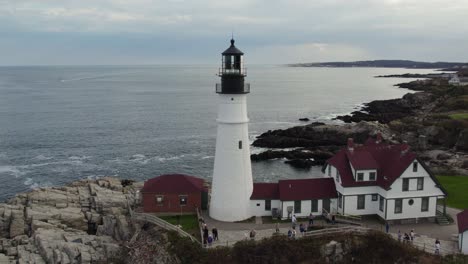 tourists visiting portland head light lighthouse in maine, aerial shot